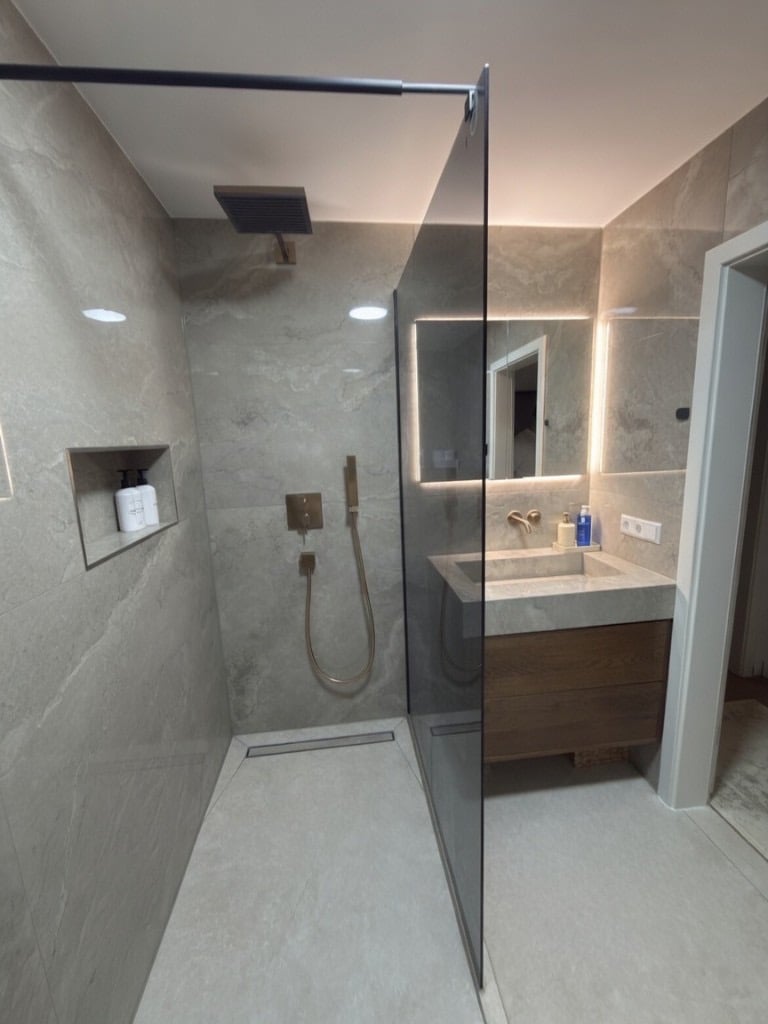 Modernisiertes Badezimmer mit Walk-in-Dusche, integriertem Waschtisch und hinterleuchtetem Spiegel