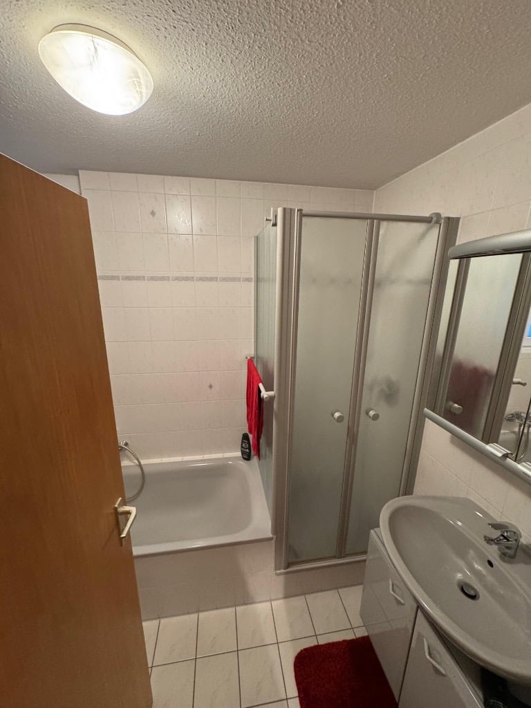 Bestehendes Badezimmer mit Waschtisch, Duschkabine und Badewanne vor der Modernisierung